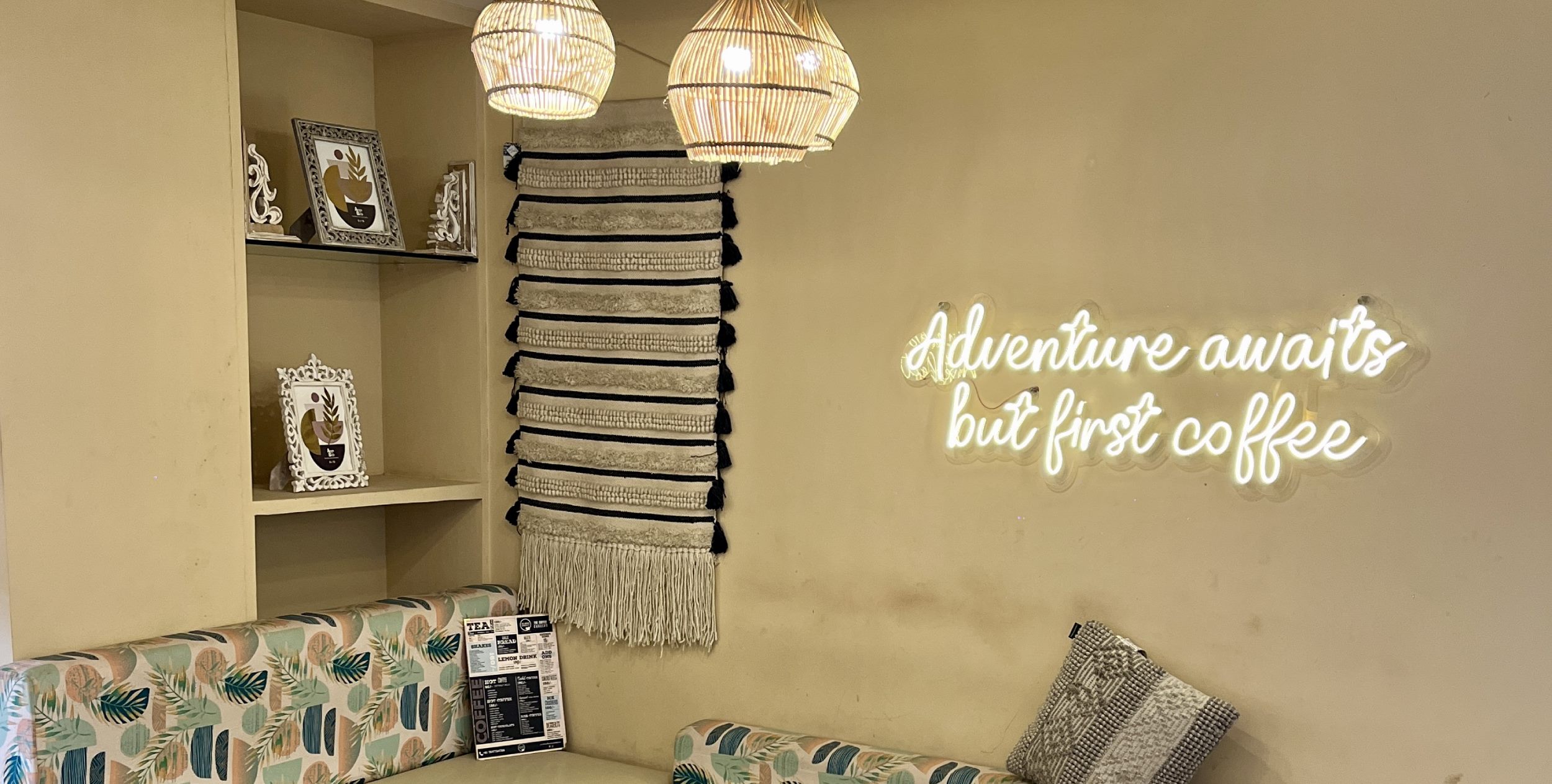 Inside The Coffee Concept — rattan lamps and a neon sign: adventure awaits, but first coffee