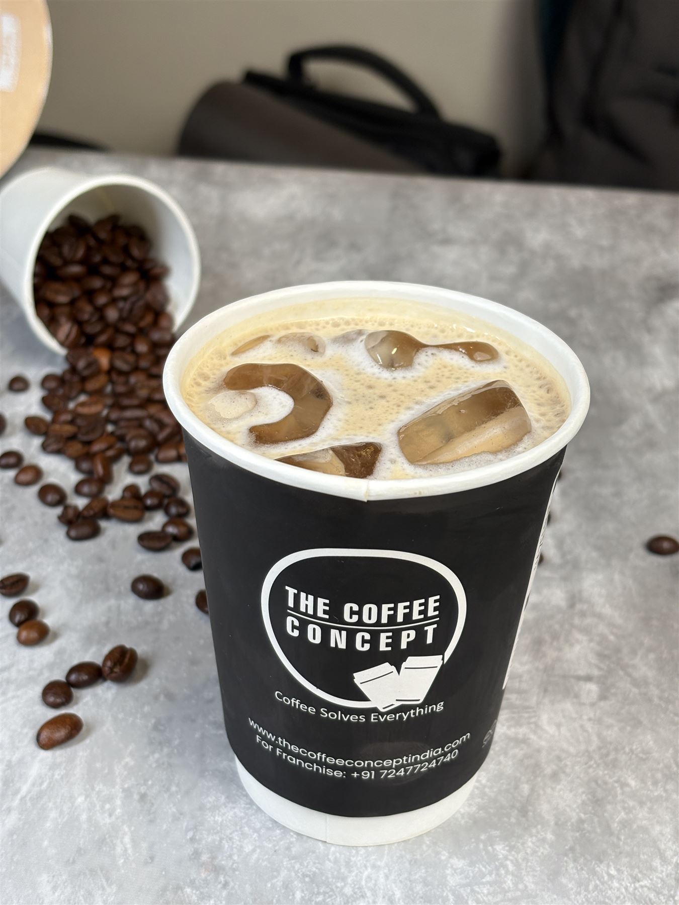 An iced latte in a TCC cup with coffee beans