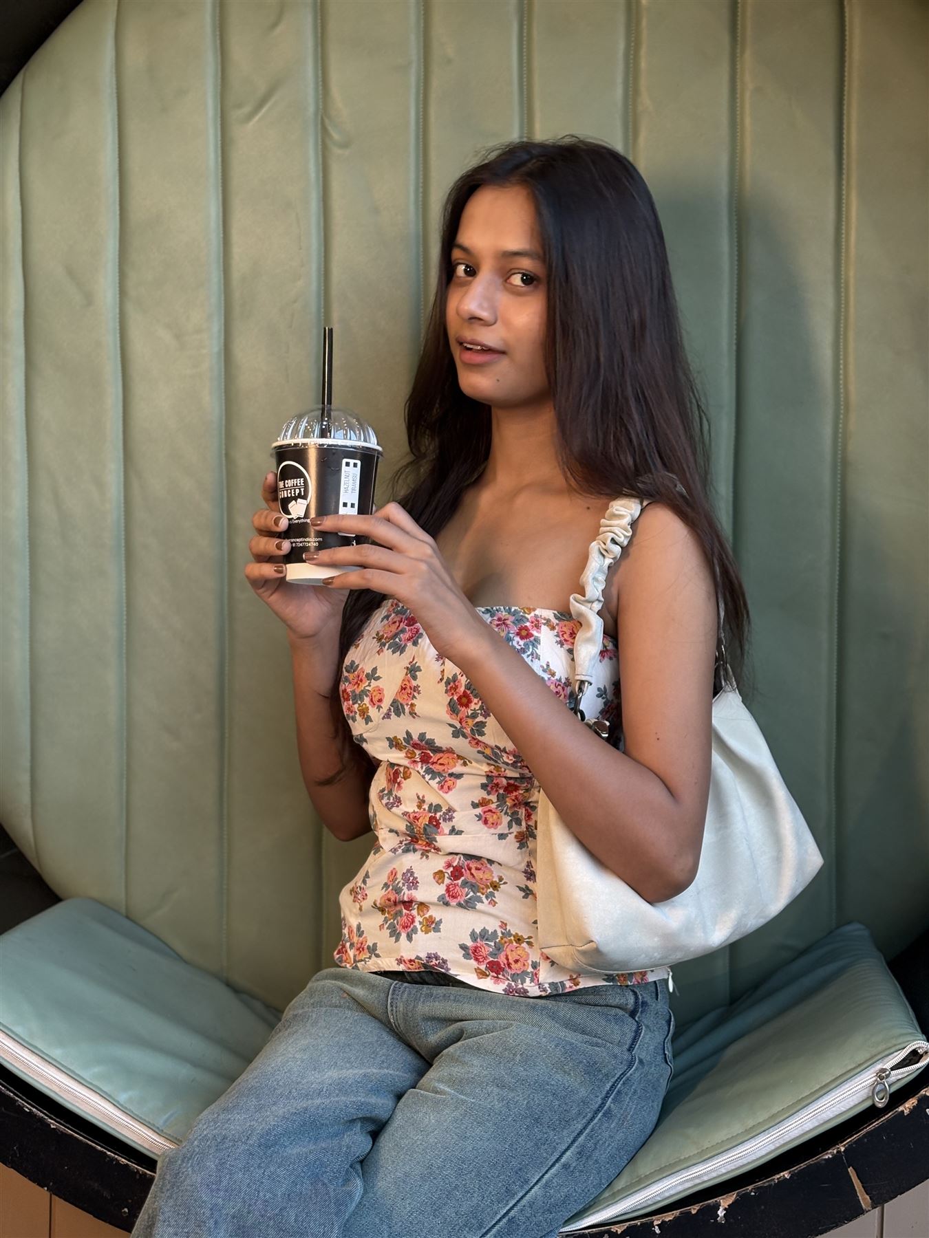 A guest with a TCC cold coffee in a green booth